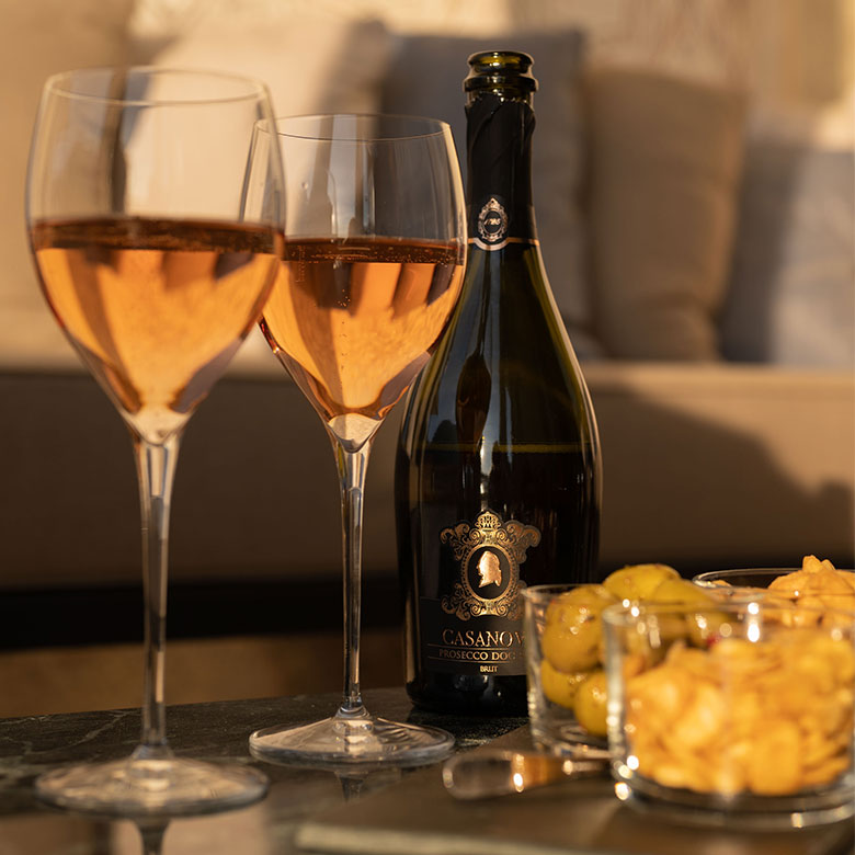 Two glasses and a bottle of Casanova Prosecco Rosé with snacks during aperitive