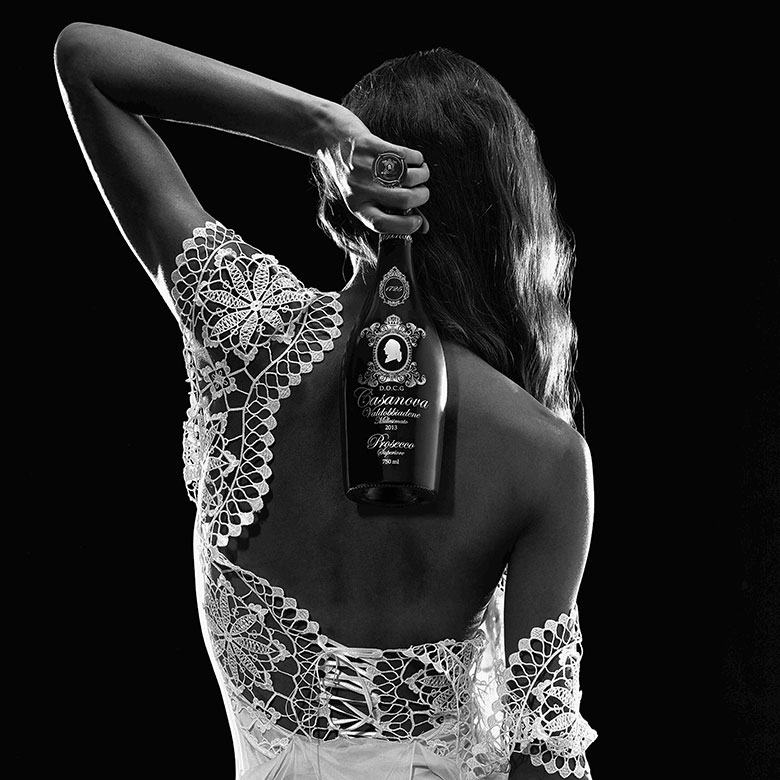 Una donna di spalle posa con una bottiglia di Casanova Prosecco DOCG Valdobbiadene Superiore